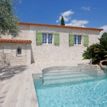 maison avec effet pierres claires et blason devant piscine