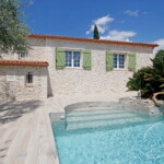 maison avec effet pierres claires et blason devant piscine