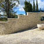 Mur de clôture en fausse pierre réalisée en enduit